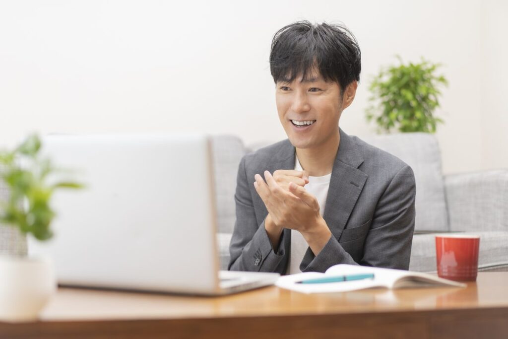 ノートパソコンの前でオンライン英会話のレッスンを楽しむ男性