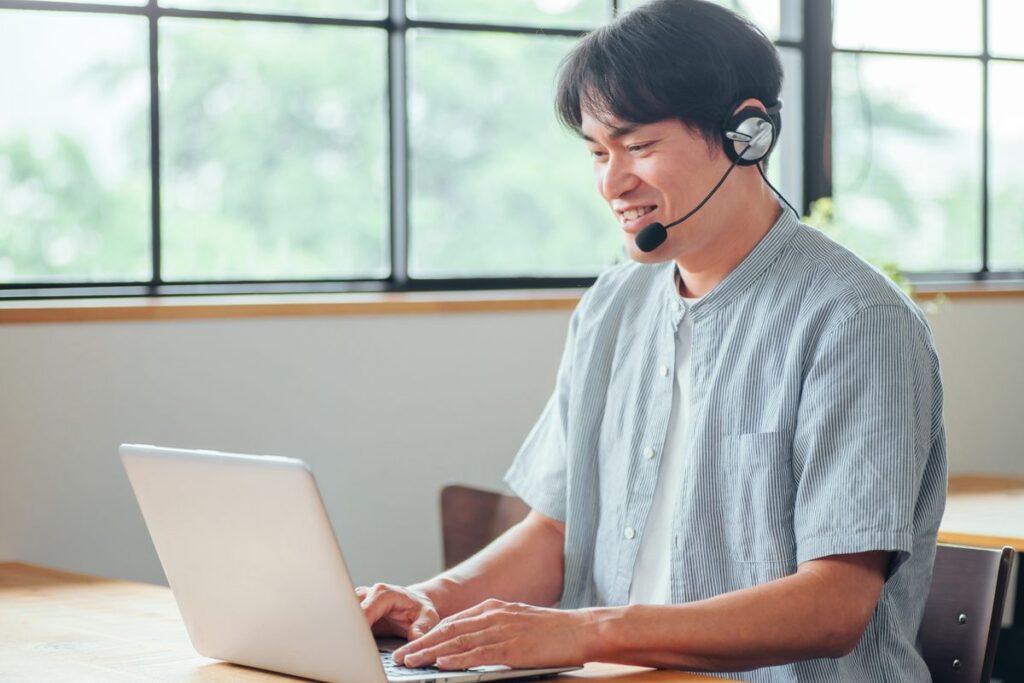ノートパソコンでオンライン英会話のレッスンを受ける男性