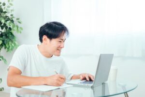 オンライン英会話のレッスンを笑顔で楽しみながら続けている男性