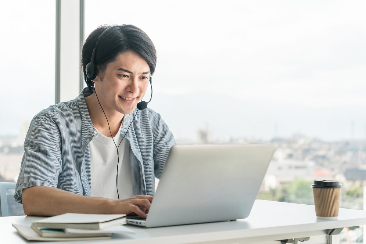 窓際のデスクでノートパソコンに向かって作業している人