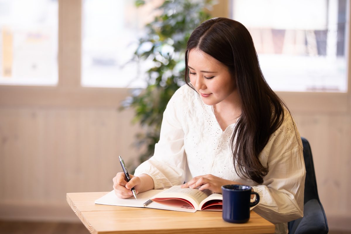 机に向かってノートに書き込みながらブログの構成を組み立てている様子